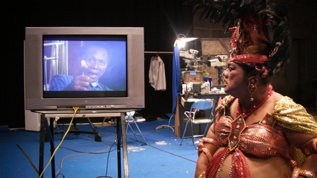 act-of-killing-the-2012-005-herman-in-drag-watching-anwar-on-tv.jpg